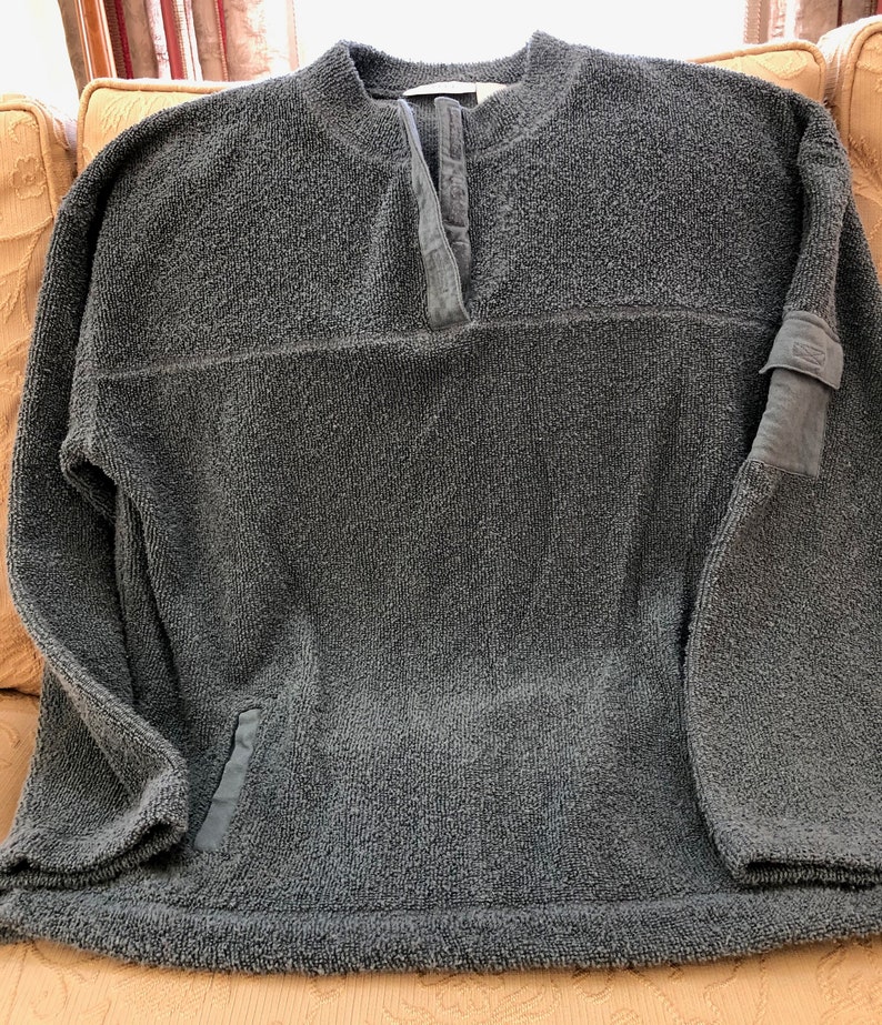 May include: A dark gray fleece pullover with a buttoned neck and a patch on the sleeve.