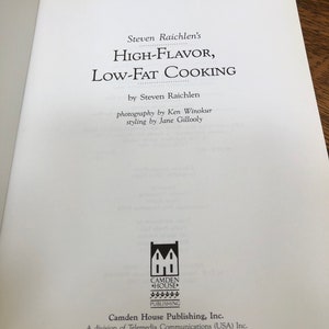 May include: A book cover with the title "High-Flavor, Low-Fat Cooking" by Steven Raichlen. The cover features a black and white illustration of a house with the words "Camden House Publishing" below it.