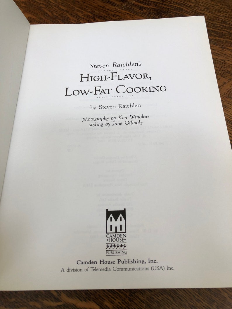 May include: A book cover with the title "High-Flavor, Low-Fat Cooking" by Steven Raichlen. The cover features a black and white illustration of a house with the words "Camden House Publishing" below it.