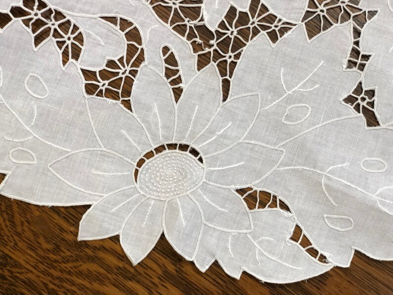 May include: White cotton lace tablecloth with a delicate floral design featuring a large sunflower in the center.