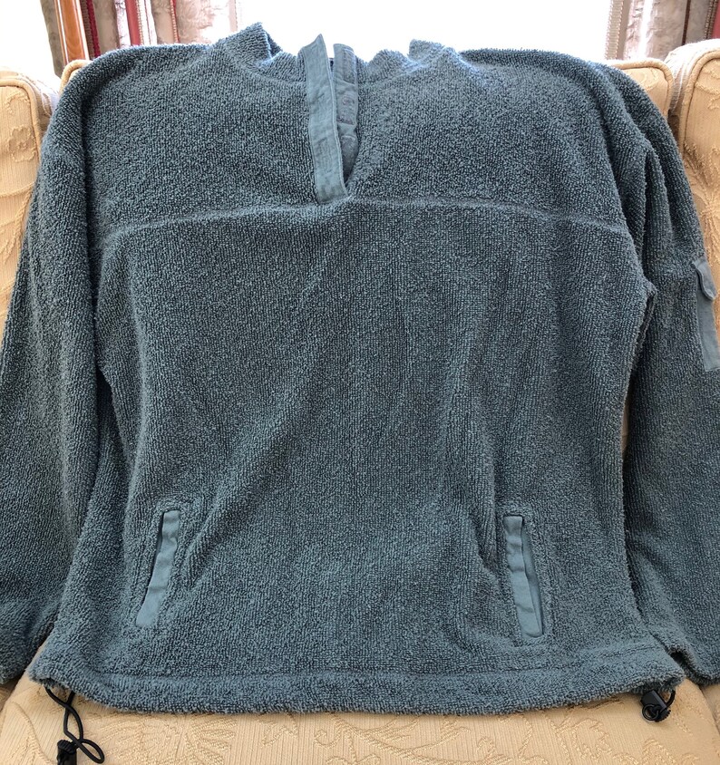 May include: A blue fleece pullover with a mock neck and long sleeves. The pullover has two pockets on the bottom and a zipper at the neck.