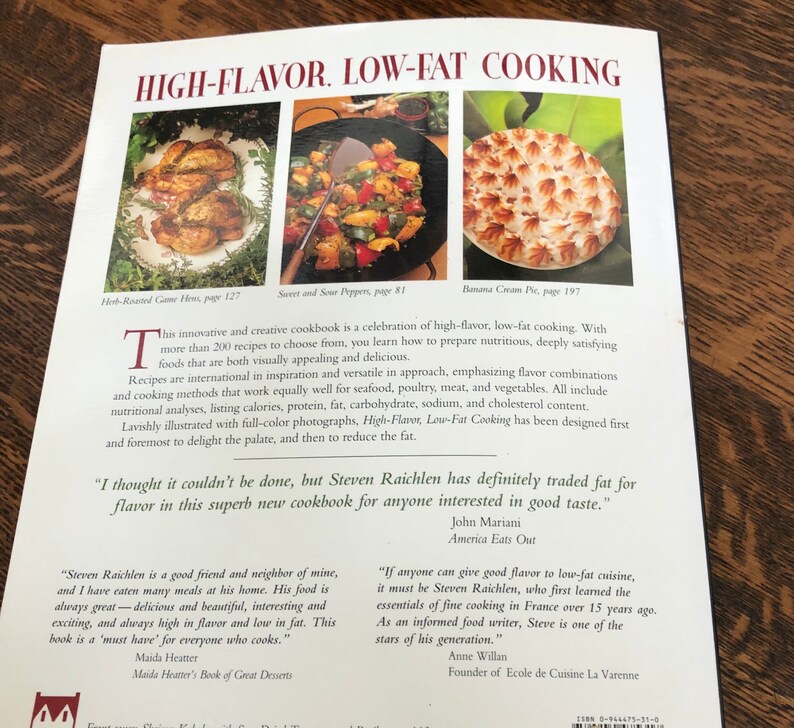May include: A book cover for a cookbook titled "High-Flavor, Low-Fat Cooking" with a colorful image of a roasted chicken, sweet peppers, and a banana cream pie. The book cover features quotes from John Mariani, Maida Heatter, and Anne Willan.
