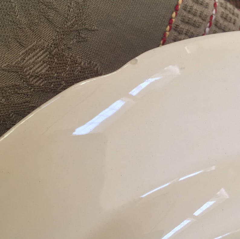 Pu&ograve; includere: Un piatto in ceramica bianca con un bordo ondulato. Il piatto ha un piccolo scheggio sul bordo.