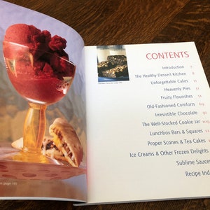 May include: A cookbook with a red and white cover and the word "CONTENTS" in large, red letters. The book features a variety of recipes, including desserts, cakes, pies, cookies, and more.