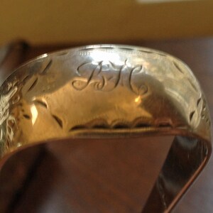 May include: A silver ring with an engraved design and the initials "B.H." on the top.