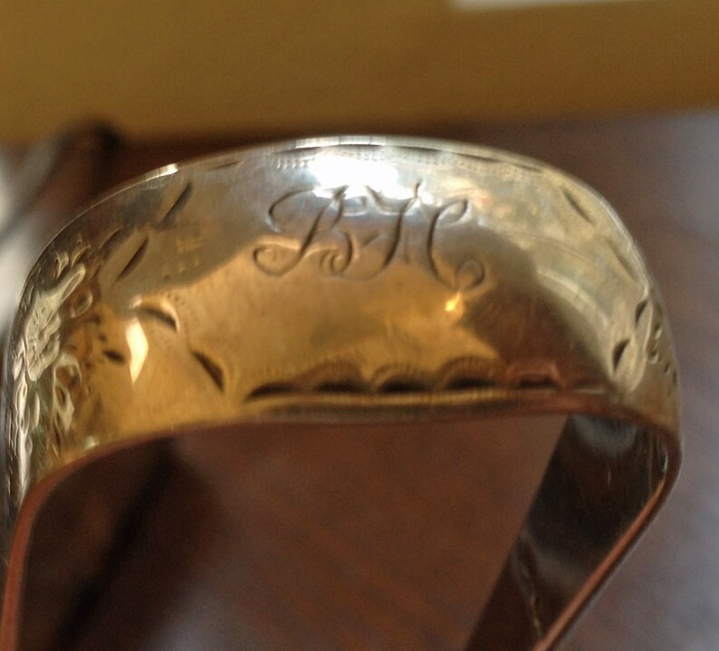 May include: A silver ring with an engraved design and the initials "B.H." on the top.