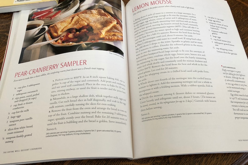 May include: A cookbook page with a recipe for Pear-Cranberry Sampler, a warm fruit dessert with a French toast topping. The recipe includes ingredients like pears, cranberries, corn starch, sugar, and bread. The image also shows a close-up of the dessert, which is baked in a square baking dish.