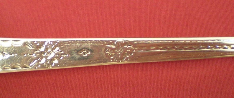 May include: Close-up of the back of a silver spoon with an ornate design and the inscription "3" on the handle.