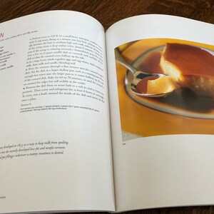 May include: A close-up of a flan dessert on a yellow plate. The flan is a light yellow color and has a smooth, creamy texture. The flan is topped with a caramel sauce. The flan is being scooped up with a silver spoon.