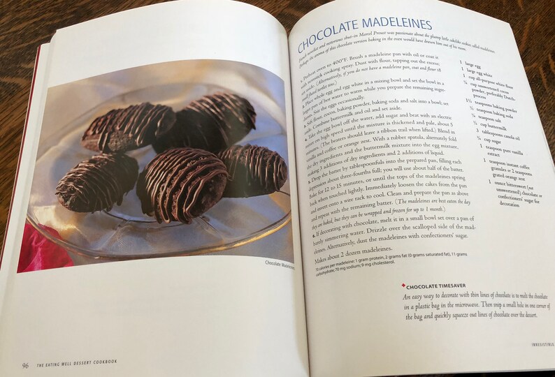 May include: A close-up of a plate of chocolate madeleines, a type of French pastry. The madeleines are topped with a chocolate drizzle and are arranged in a circular pattern on the plate.