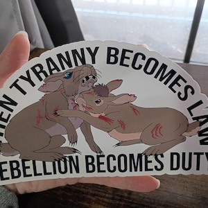 May include: A sticker with a design of two fighting rabbits, with blood marks, and the text "WHEN TYRANNY BECOMES LAW REBELLION BECOMES DUTY" in an arch above and below the image.
