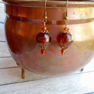 May include: A pair of dangle earrings with amber-colored glass beads and gold-toned metal accents.