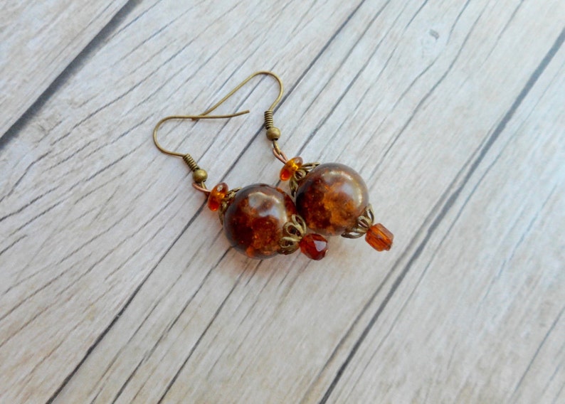 May include: A pair of dangle earrings with brown glass beads and gold-toned metal accents.