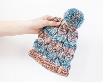 Colourful hand knitted cable pom pom hat. Women's thick chunky bobble beanie. Blue/Rust brown, variegated yarn, textured winter accessory.