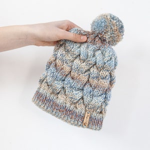 Colourful hand knitted cable pom pom hat. Women&#39;s thick chunky bobble beanie. Blue/Grey mix, variegated yarn, textured winter accessory.