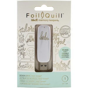 May include: White USB drive with gold foil lettering that reads "Heidi Swapp" on the front. The drive is packaged in a clear plastic case with a white background and gold foil lettering that reads "Foil Quill We R memory keepers." The packaging also features a variety of gold foil designs, including hearts, stars, and a pineapple.