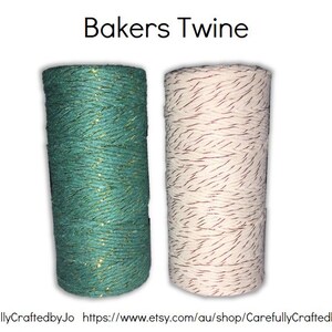 May include: Two spools of bakers twine. One spool is teal with gold glitter and the other is white with brown stripes.