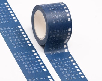 May include: A blue washi tape with white numbers 1 through 31 printed on it. The tape is rolled up and partially unrolled, showing the numbers in a repeating pattern. The tape is on a white background.