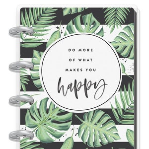 Peut inclure: Un agenda rayé noir et blanc avec un motif de feuilles tropicales. L'agenda a une couverture transparente et un cercle blanc avec le texte "Faites plus de ce qui vous rend heureux".
