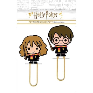May include: Two gold paper clips with Harry Potter and Hermione Granger characters attached. The characters are in a cartoon style and are holding wands. The packaging says "Harry Potter Puffy Clips | Attaches Puffy | 2pc/pcs/piezas".