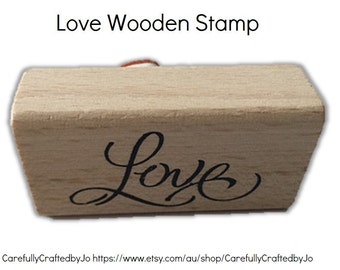 Könnte beinhalten: Ein Holzstempel mit dem Wort "Love" in einer kursivschrift.