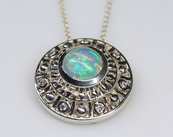 May include: A silver necklace with a round pendant featuring a green and blue opal surrounded by a decorative border of silver and small diamonds.