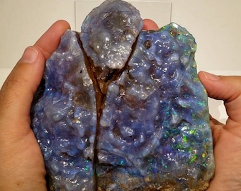 May include: A large, rough, blue opal with iridescent flashes of green and purple. The opal is split in two pieces, with a natural crack running through the centre.
