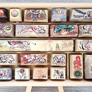 Könnte beinhalten: Eine Holzkiste gefüllt mit benutzerdefinierten Tastaturkappen mit verschiedenen Designs, darunter ein Fuchs, ein Tiger, ein Drache und eine Bergszene. Die Tastenkappen sind in Reihen angeordnet und mit Buchstaben und Symbolen wie "Tab", "Shift", "Enter" und "Ctrl" beschriftet.