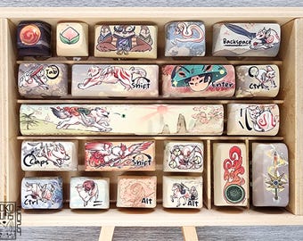 May include: A wooden box filled with custom keyboard keycaps featuring various designs, including a fox, a tiger, a dragon, and a mountain scene. The keycaps are arranged in rows and labeled with letters and symbols, such as "Tab", "Shift", "Enter", and "Ctrl".