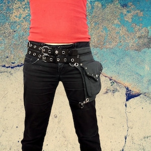 May include: A black leather belt with multiple silver buckles and a black canvas fanny pack with silver accents.