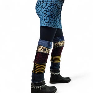 Op de afbeelding: Een persoon draagt een blauwgepatroneerde minirok over een zwarte legging, gecombineerd met patchwork beenwarmers en zwarte laarzen. De beenwarmers hebben denim, luipaardprint en gestreepte secties, waardoor een unieke, gelaagde look ontstaat.