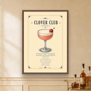 May include: A framed wall art print featuring a Clover Club cocktail illustration. The design includes a pink drink in a coupe glass with a raspberry garnish, the text Clover Club Cocktail, and a list of ingredients in ounces and milliliters.