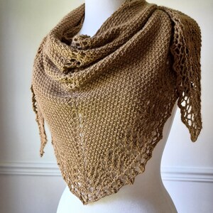 May include: A brown knitted shawl with a delicate lace trim. The shawl is draped over a white mannequin.