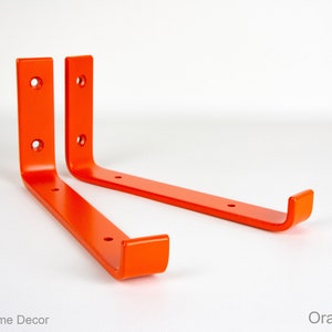 May include: Two bright orange metal shelf brackets with rounded edges and four holes each.  Orange Matte.