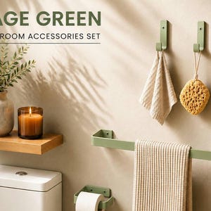 Può includere: Un set di accessori da bagno color verde salvia che include due ganci a parete, un portasciugamani e un portarotolo. Il testo SAGE GREEN BATHROOM ACCESSORIES SET è visibile in alto. Il set presenta una finitura opaca e una struttura in metallo.