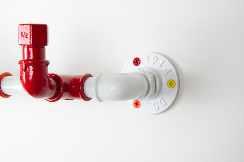May include: A red and white pipe fitting with a white flange. The flange has the text "DS 1914" on it. The pipe fitting has a red elbow and a red cap with the text "5/2" on it.