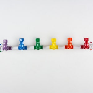 May include: A white metal pipe with seven colourful hooks. The hooks are in the colours of the rainbow, starting with purple and ending with red.