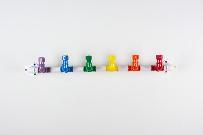 May include: A white metal pipe with seven colourful hooks. The hooks are in the colours of the rainbow, starting with purple and ending with red.