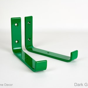 May include: Two dark green gloss metal shelf brackets. The brackets are L-shaped and have three holes on the vertical side and one hole on the horizontal side.