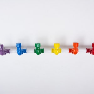 May include: A white metal pipe with six colourful hooks. The hooks are purple, blue, green, yellow, orange and red.