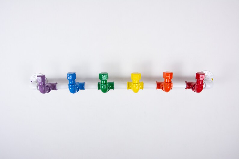 May include: A white metal pipe with six colourful hooks. The hooks are purple, blue, green, yellow, orange and red.