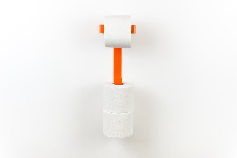 Op de afbeelding: Een oranje toiletpapierhouder met een verticaal ontwerp. De houder is aan een witte muur bevestigd en bevat &eacute;&eacute;n rol toiletpapier aan de bovenkant en twee rollen aan de onderkant. De houder is gemaakt van plastic.