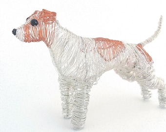 May include: A wire sculpture of a dog, primarily silver with copper-colored accents. The dog is standing, with its head and patches on its back in copper. The sculpture is made of coiled wire, giving it a textured appearance.