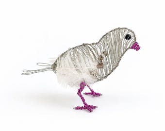 May include: A bird figurine crafted from silver-toned wire with a white feathered body. The bird features a small black bead for an eye, a bright magenta wire beak, and matching magenta wire legs and feet. The tail is formed from looped wire.