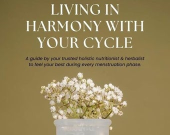 Puede incluir: Una copa menstrual blanca con un ramo de flores blancas en la parte superior. El texto "LIVING IN HARMONY WITH YOUR CYCLE" está en la parte superior de la imagen. El texto "CASSANDRA PERRY FT. MELANIE RAVEY" está en la parte inferior de la imagen.