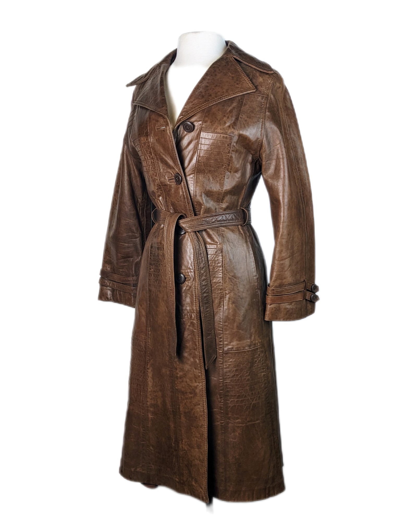 Vintage leather 1970s chocolate brown trench coat with single breasted fastening, self-tie belt, and side slant pockets.
