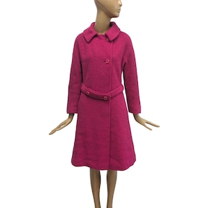 May include: A vintage magenta coat with a textured weave. The coat features a rounded collar, long sleeves, and a matching belt that cinches at the waist. The coat measures approximately 102 cm in length.