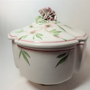 May include: White ceramic serving dish with a lid and three compartments. The lid features a pink carnation and a floral design with pink flowers and green leaves.
