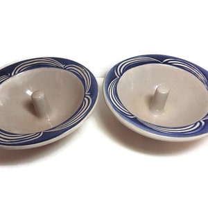 May include: Two ceramic ring dishes with a blue and white design. Each dish has a small, raised center post.