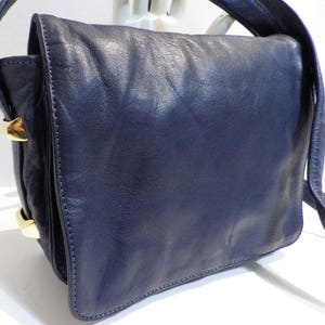 May include: A dark blue leather shoulder bag with gold-toned hardware. The bag has a flap closure and a single strap.
